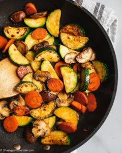 Zucchini, carrot slices, and mushrooms lightly browned in a skillet, showing a simple soy free vegetable stir fry.