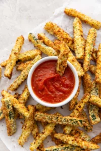 air fryer zucchini fries around a dish of marinara sauce