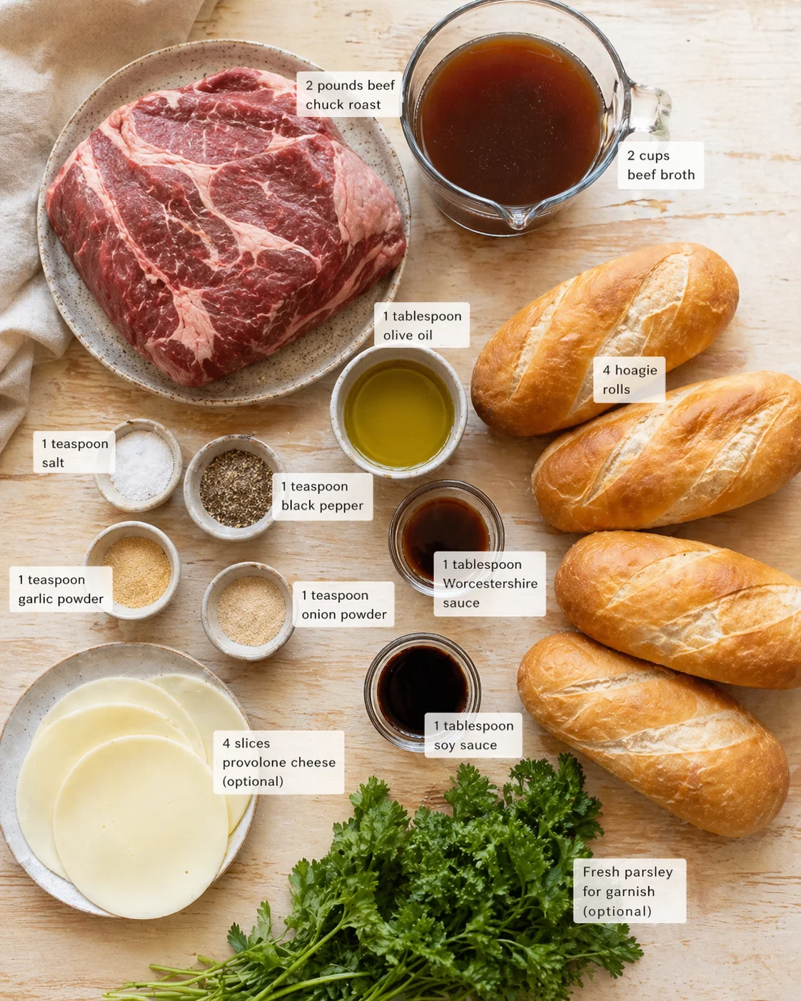 Top-down view of beef, bread rolls, cheese, oils, and spices arranged for a recipe.