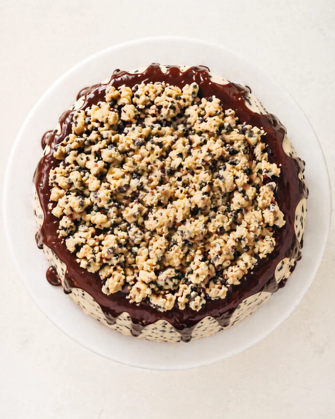 top-down view of a round cake with dark chocolate glaze and crumb topping on a white plate