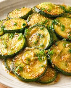 glossy pan-seared zucchini slices drizzled with glaze and sprinkled with sesame and green onions.