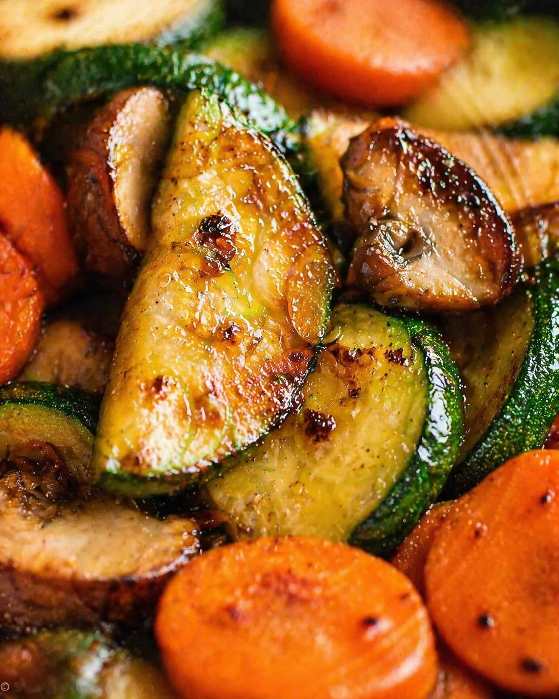 close-up of glossy roasted zucchini slices and carrot rounds with caramelized edges