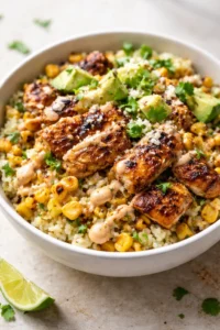 seared protein chunks on corn and grain base, topped with avocado and cilantro