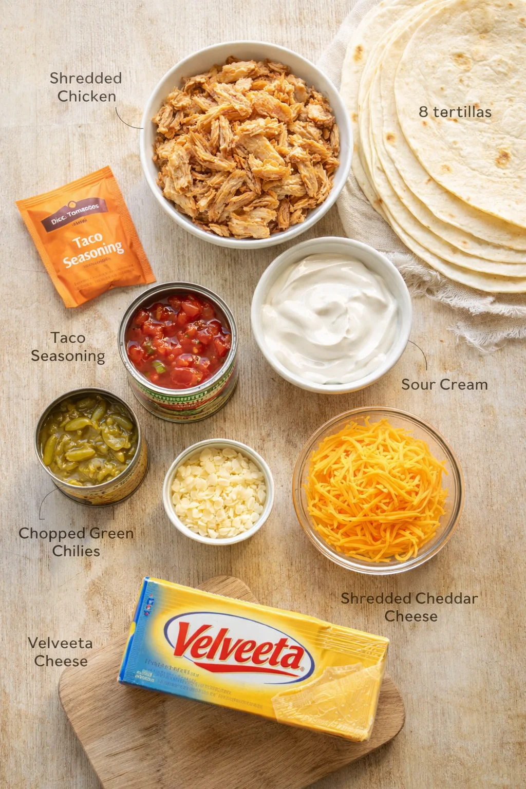 Overhead view of a taco-ingredient layout with shredded chicken, tortillas, salsa, sour cream, and cheese.