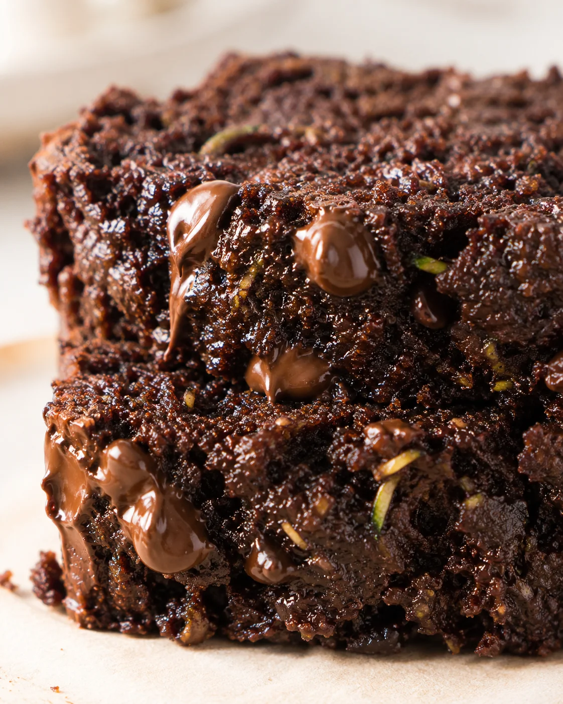 Close-up of a fudgy chocolate brownie with melty chocolate chunks and pistachio pieces.