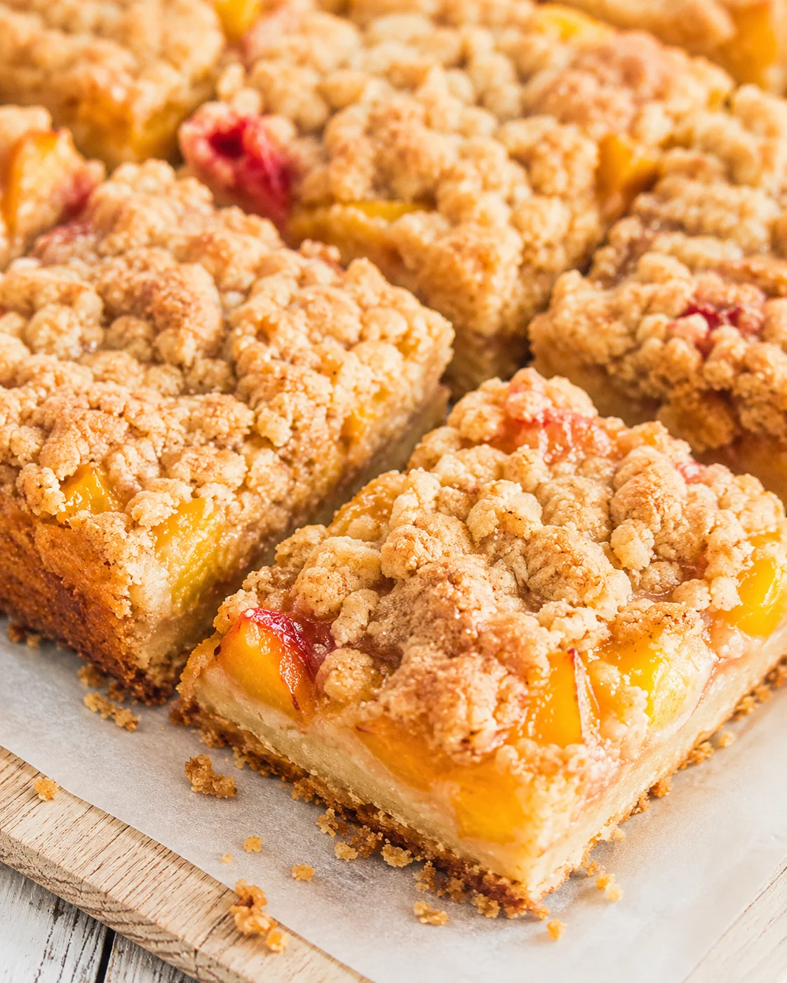 close-up of peach crumble bars with crumb topping on parchment