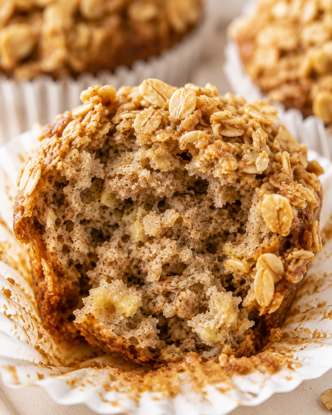 Close-up of a moist banana oatmeal muffin with oat topping and bites taken out