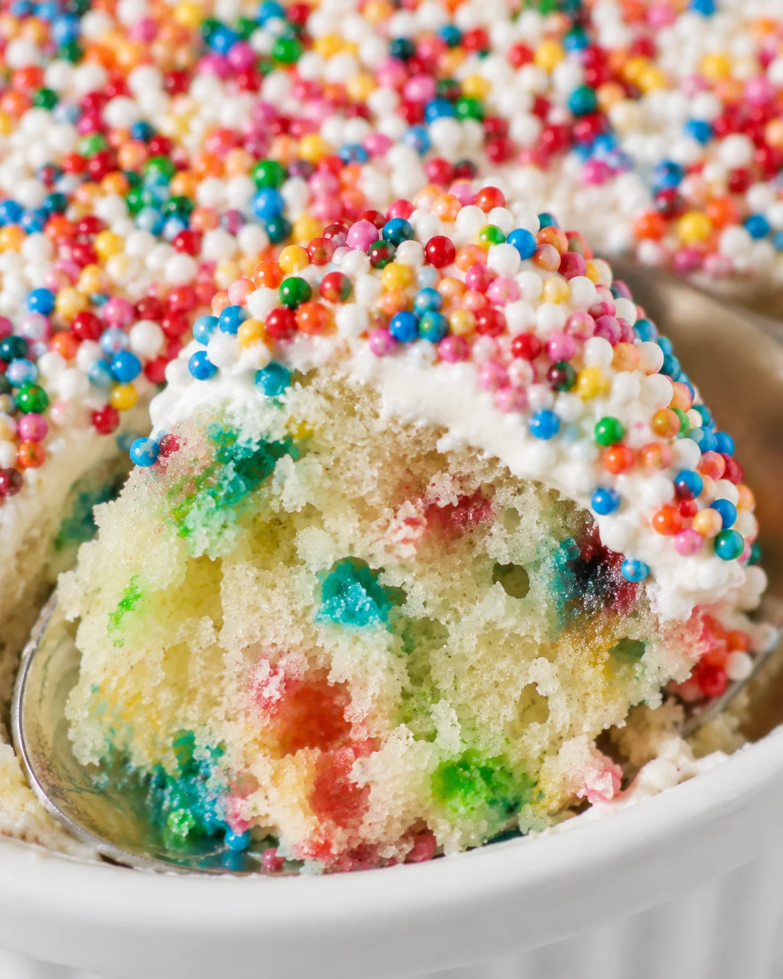 Close-up of a colorful funfetti dot cake topped with sprinkles in a ramekin.