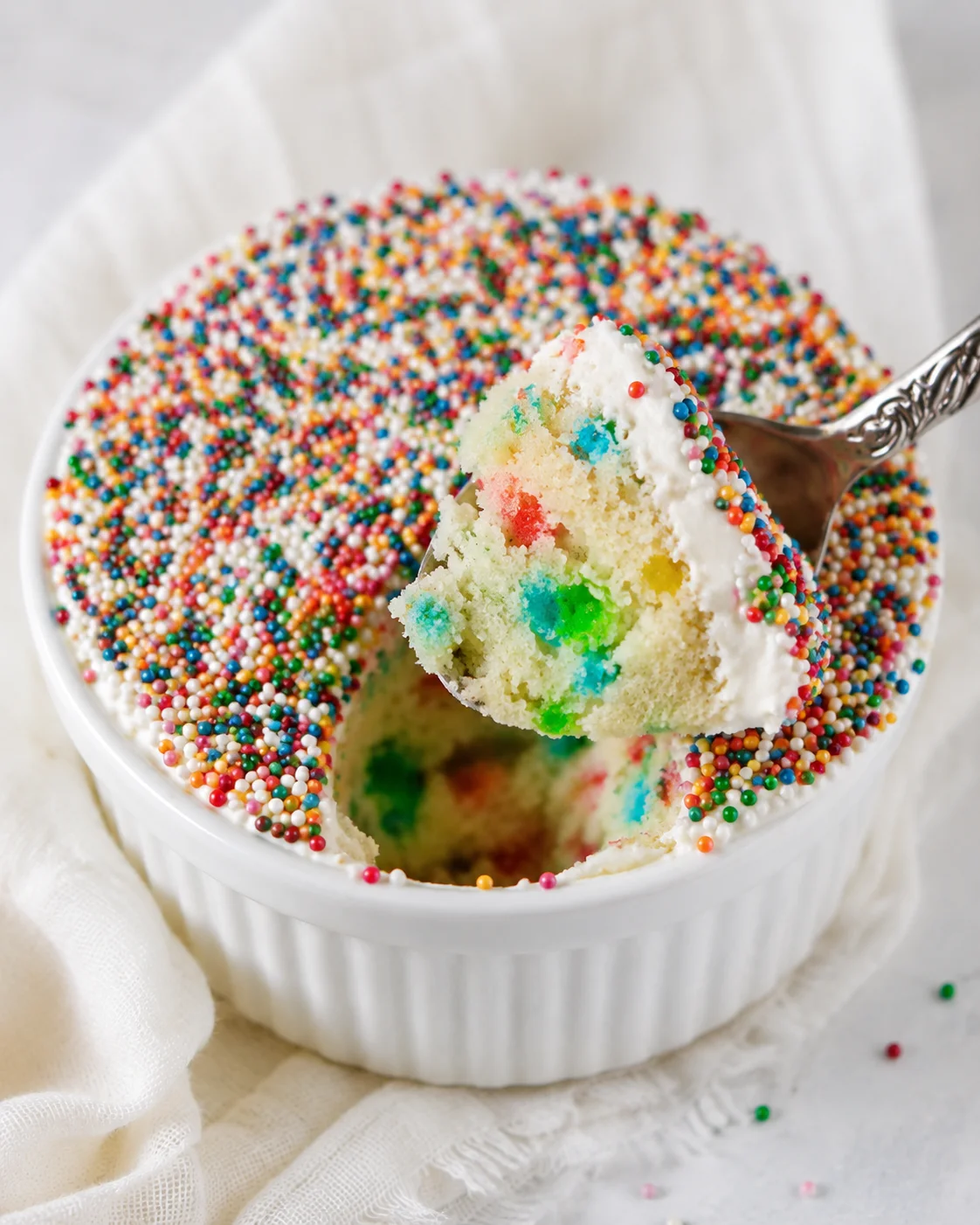 Cute mini funfetti dot cake topped with sprinkles in a ramekin.