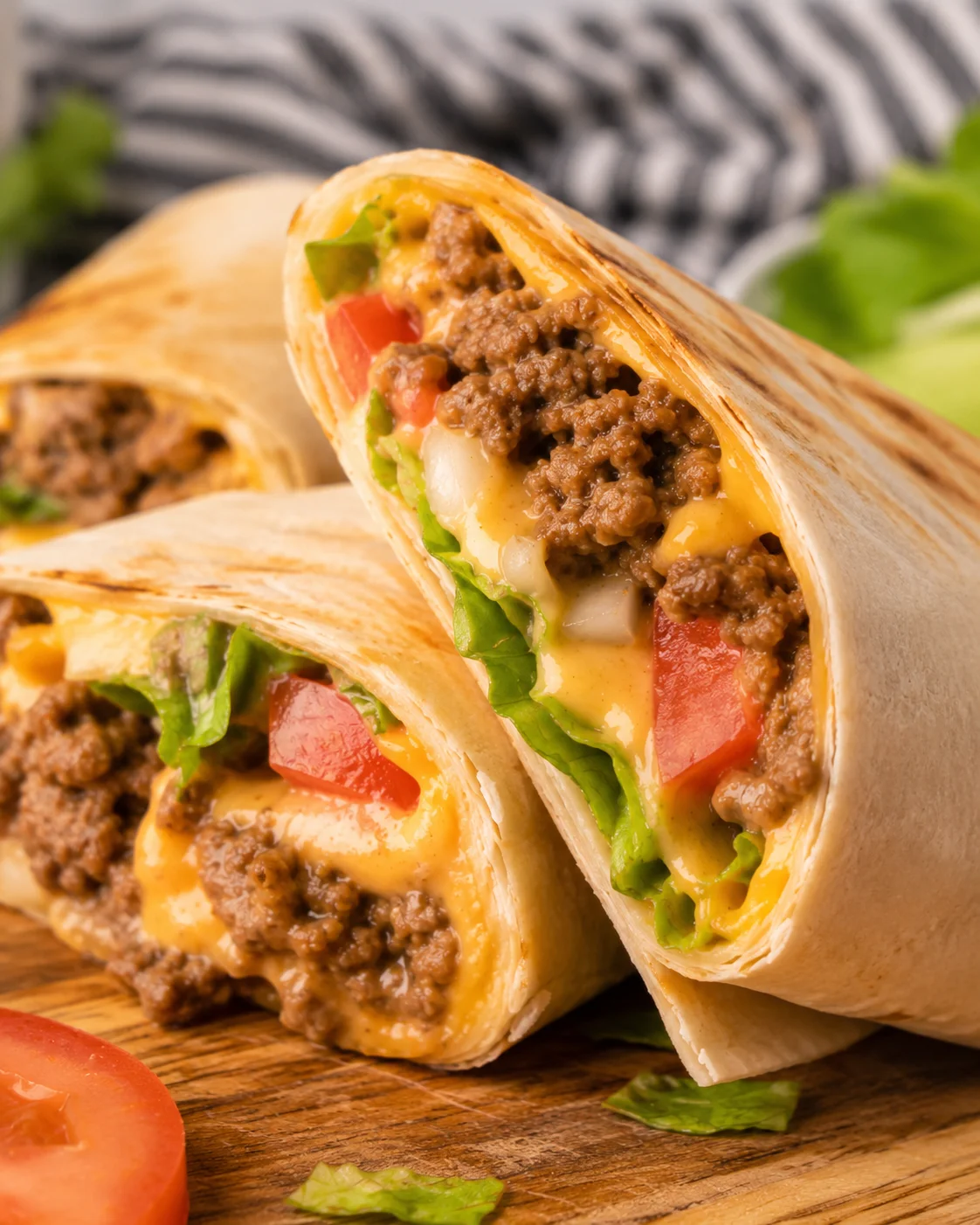 Close-up of a delicious sliced cheeseburger wrap filled with seasoned beef, cheese, and toppings