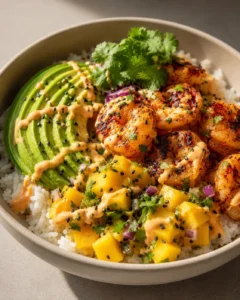 Colorful shrimp, avocado, mango, and rice served in a bowl with cilantro