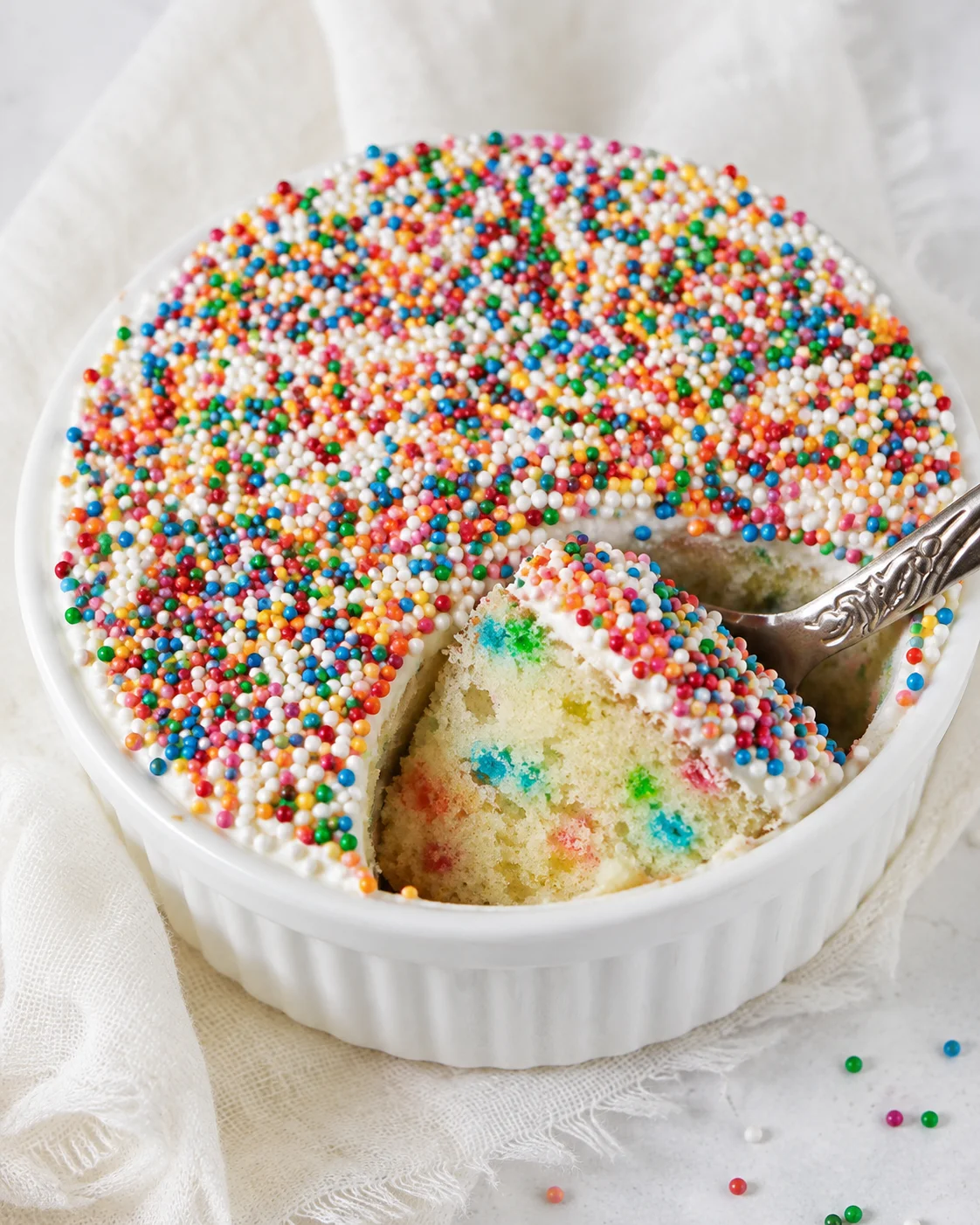Adorable mini dot cake topped with colorful sprinkles and homemade frosting.