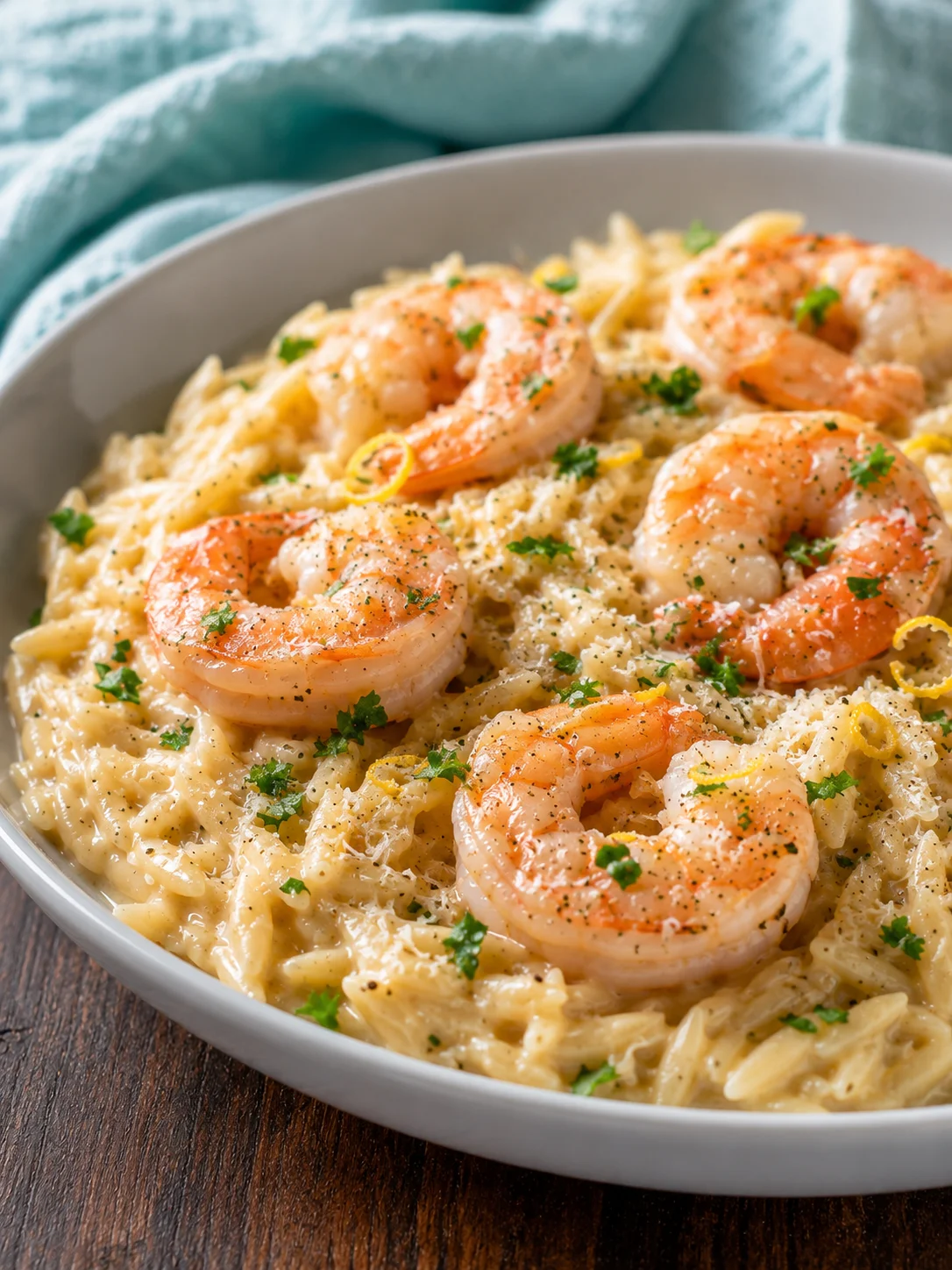 Creamy shrimp orzo dish with herbs and lemon, served in a white bowl.