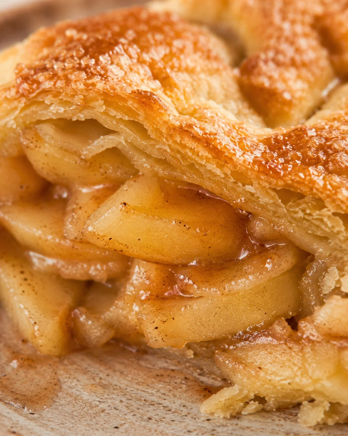 Close-up of a freshly baked apple pie with golden, flaky crust and tender apple filling.