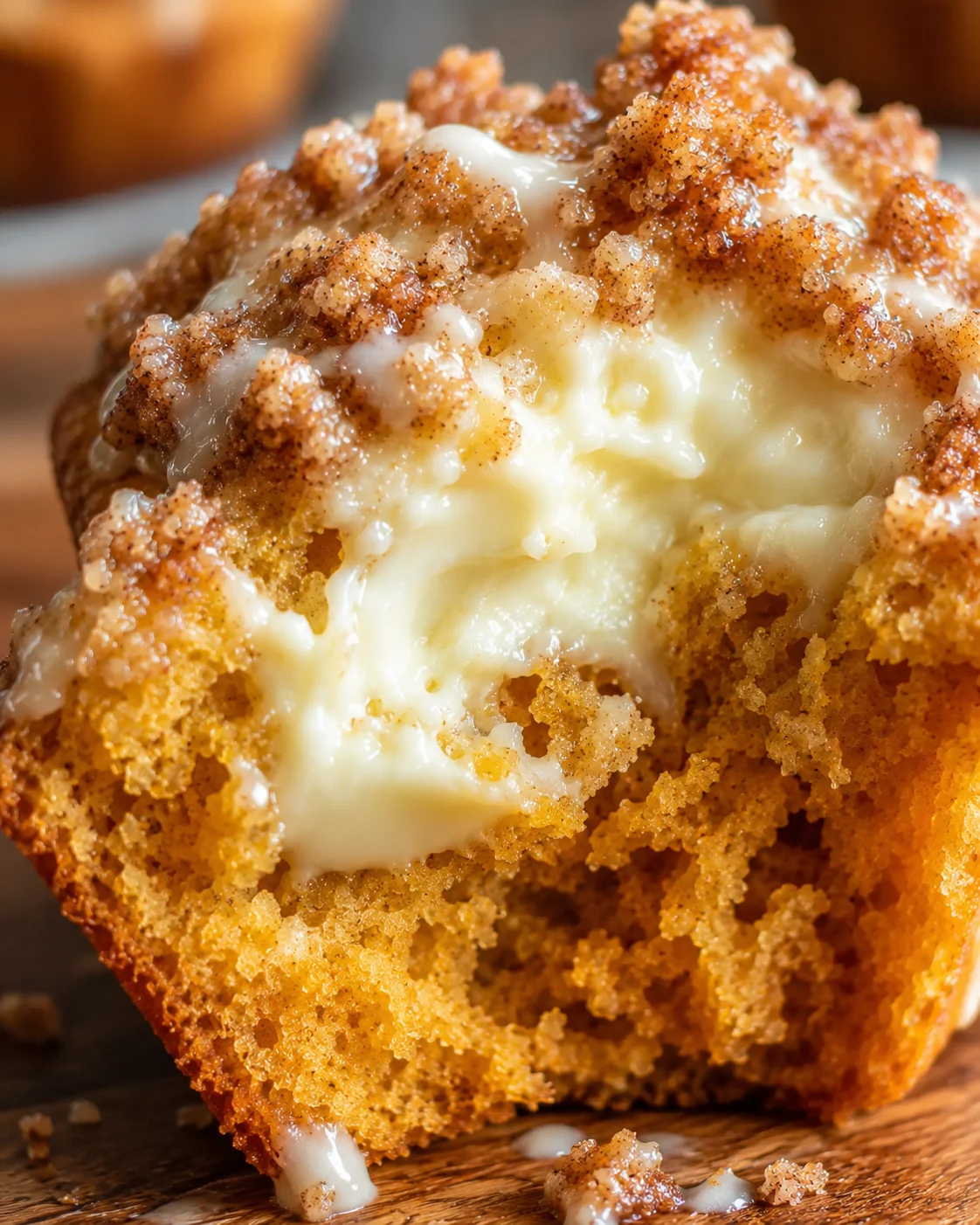Close-up of a freshly baked muffin with cream cheese filling and streusel topping.