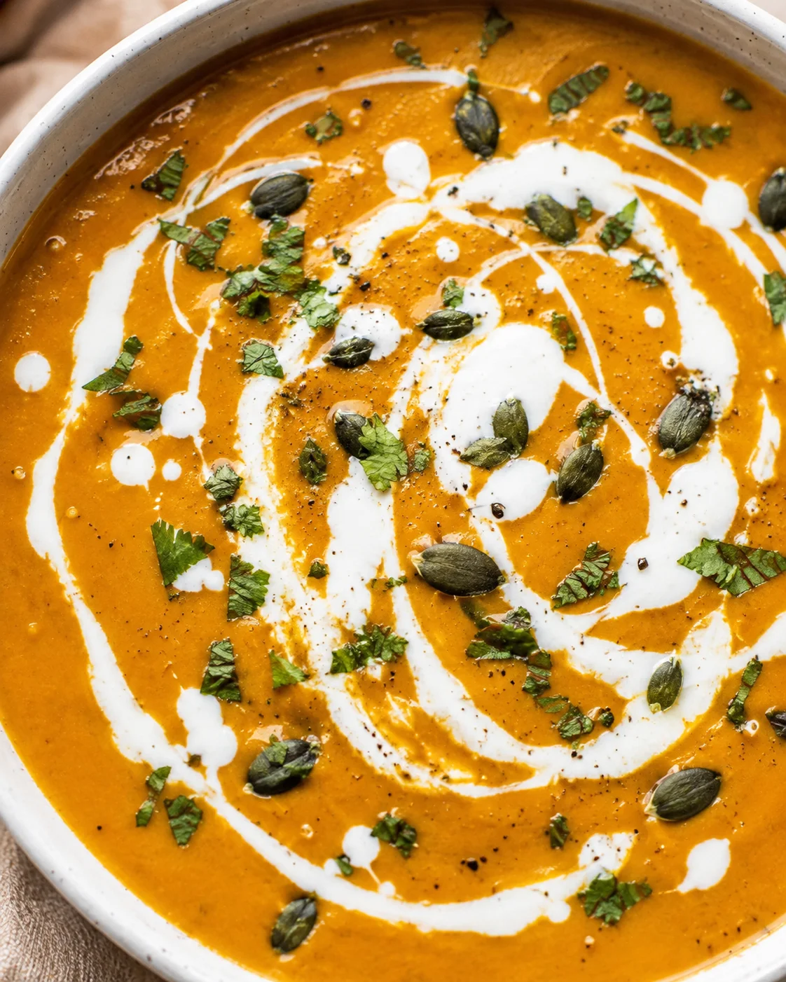 Velvety pumpkin curry soup topped with coconut milk and pumpkin seeds.