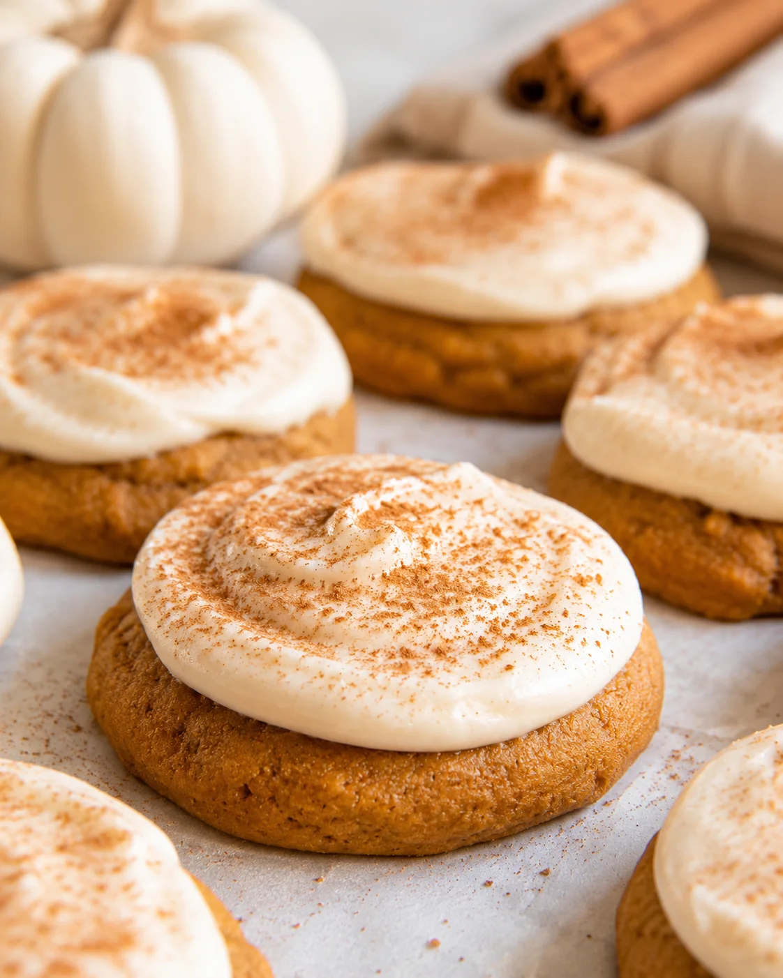 Close-up of fluffy pumpkin cookies topped with cream cheese frosting and cinnamon