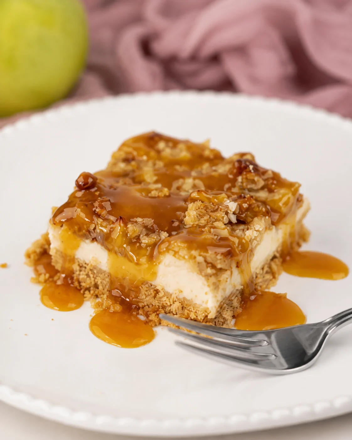 Delicious caramel apple cheesecake bars with streusel topping and caramel drizzle.