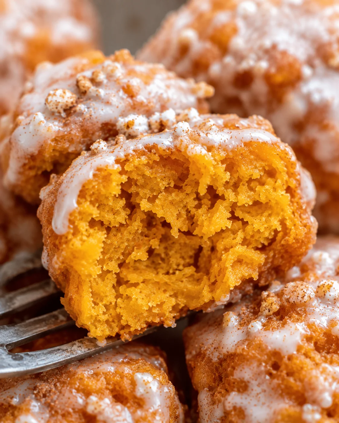 Close-up of fluffy baked pumpkin fritter bites topped with glaze and cinnamon