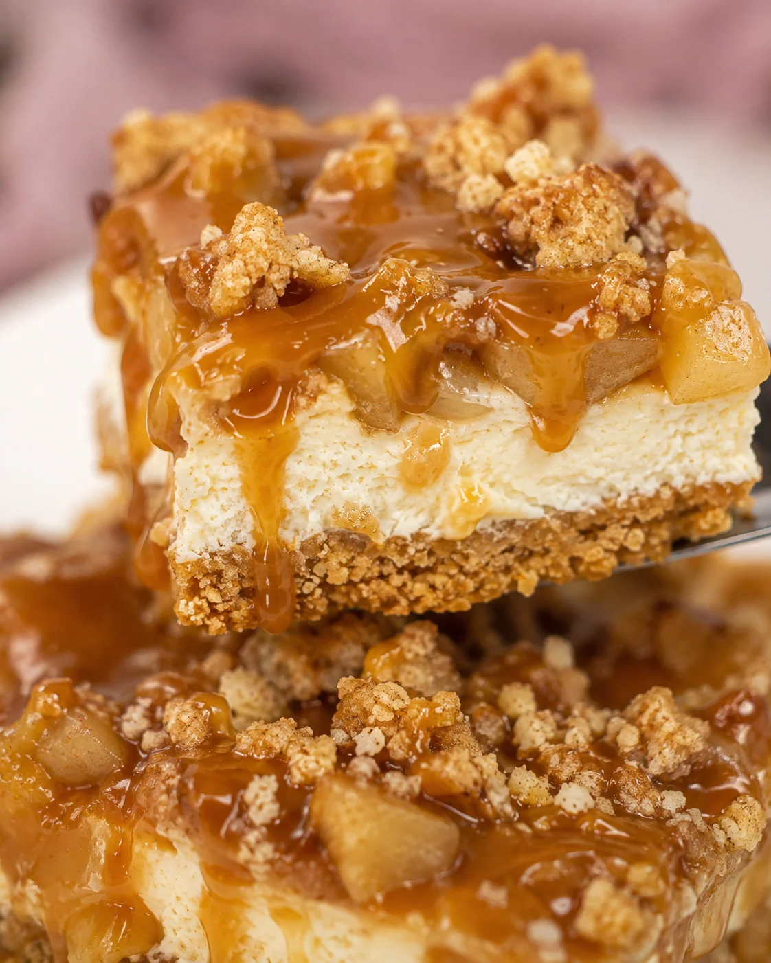 Close-up of caramel apple cheesecake bars topped with streusel and caramel drizzle.
