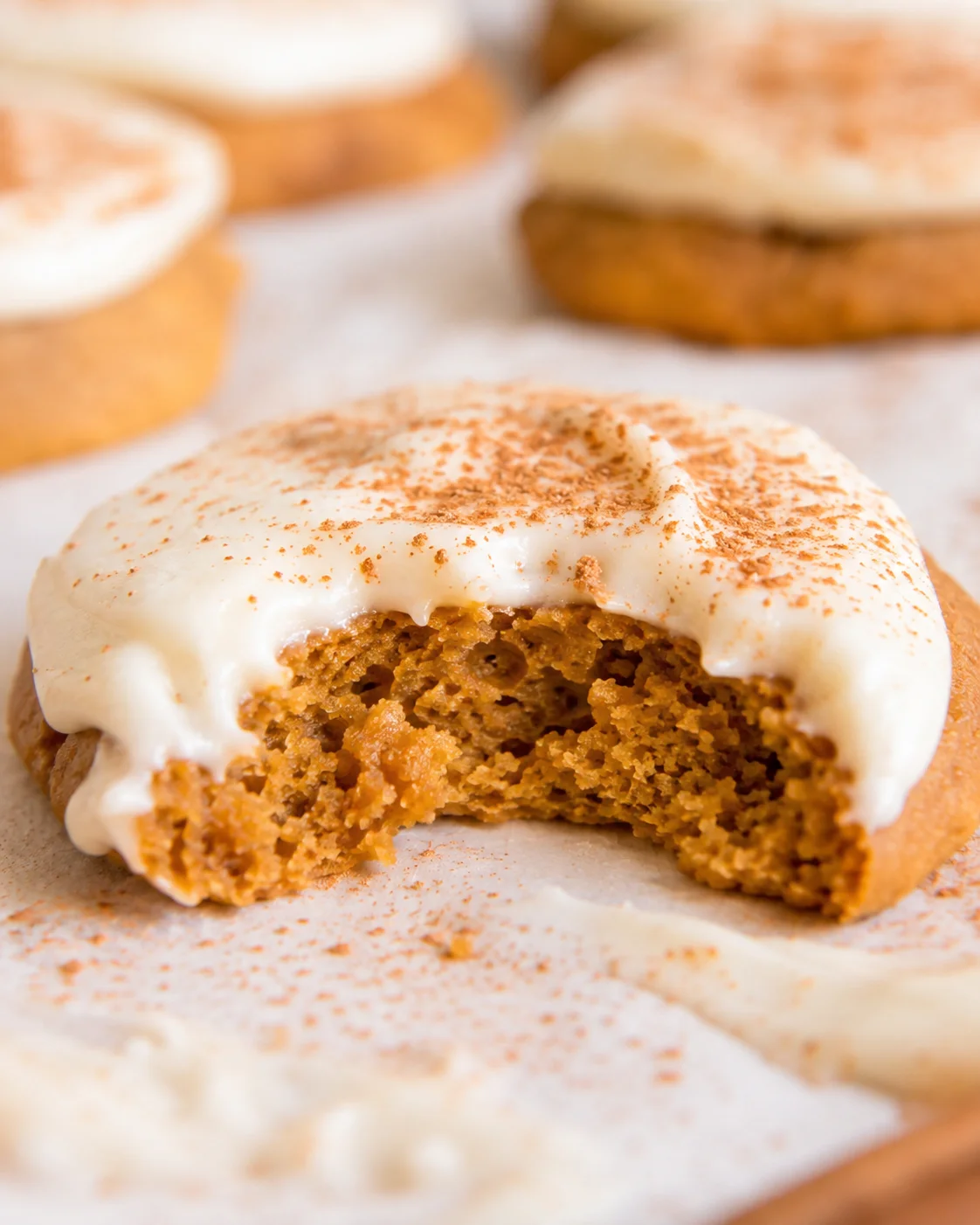 Close-up of a soft pumpkin cookie with cream cheese frosting and a bite taken out